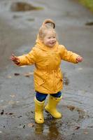 een klein meisje loopt met een paraplu in gele rubberen laarzen en een waterdichte regenjas. herfst wandeling. foto