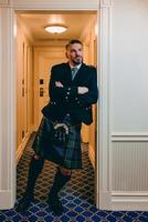 knappe volwassen moedige stijlvolle man scotsman in kilt in mooie hotelkamer. stijl, mode, lifestyle, cultuur, reizen, etnisch concept. foto