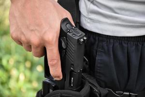 automatisch 9 mm-pistool in de hand bij de holster, klaar om uit te trekken en klaar om te schieten op het doel dat voor je ligt, concept voor beveiligingsberoep en schietsport over de hele wereld. foto