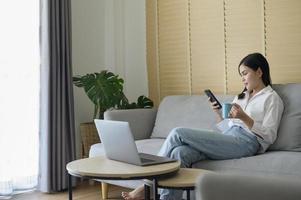 jonge gelukkige vrouw ontspannen en het gebruik van slimme telefoon thuis, sociale media en technologie concept. foto