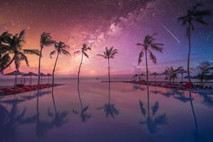 luxe infinity pool zonsondergang, nachtelijke hemel, melkweg. zomer hotel resort aan het strand in tropisch landschap. rustige strandvakantie vakantiestemming. geweldig uitzicht op het strand bij zonsondergang op het eiland, zwembad met palmen foto