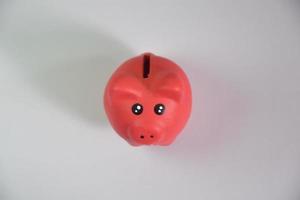 geld sparen voor toekomstige financiële stabiliteit door een spaarvarken te laten vallen, een roze spaarvarken werd naast een stapel gouden munten geplaatst. foto