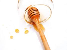 bovenaanzicht van honing stick in lege honing glazen pot met vlek van honing geïsoleerd op een witte achtergrond. foto