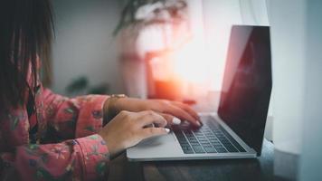 aziatische vrouw die op laptop werkt terwijl ze in een creatief kantoor of café zit. Aziatisch meisje werkt met laptop op de houten tafel in het café. foto