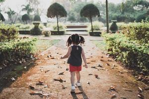 gelukkig baby Aziatisch meisje lacht. klein meisje loopt bij zonsondergang happy baby girl glimlachen. klein meisje loopt bij zonsondergang. schattig babymeisje dat in de tuin van de speelplaats loopt. foto