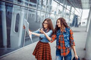 twee jonge mooie meisjes studeren en kijken naar de map.ar foto