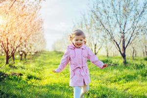 klein meisje van 3 jaar, dat tussen bloeiende bomen loopt outd foto