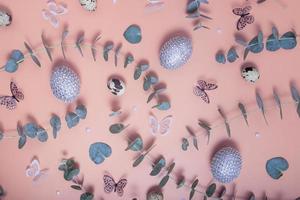 patroon van paaseieren, eucalyptus, vlinders en kralen. trendy platliggende compositie op gekleurde achtergrond foto