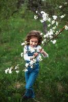 een schattig klein meisje van 5 jaar oud in een bloeiende witte appelboomgaard in het voorjaar. lente, boomgaard, bloei, allergie, lentegeur, tederheid, zorg voor de natuur. portret foto