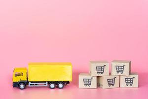 logistiek en bezorgservice - vrachtwagen en papieren dozen of pakket met een winkelwagentje-logo op roze achtergrond. winkelservice op het online web en biedt thuisbezorging. foto