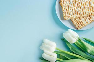 gelukkig Pascha-concept. matze en witte tulpen op een blauwe achtergrond. religieuze joodse feestdag pesach. foto