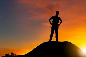 silhouet van ingenieur man met uitknippad op een bergtop zonsondergang avond hemel achtergrond foto