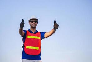 vrolijke fabrieksarbeider die lacht met duimen omhoog als teken van succes foto