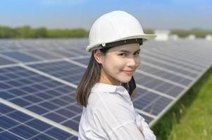 vrouwelijke ingenieur met helm in fotovoltaïsche celboerderij of zonnepanelenveld, milieuvriendelijke en schone energie. foto