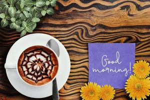 warme koffiemok met notitie Goedemorgen op een papier op houten tafel achtergrond. foto