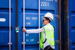 vrouwelijke ingenieur die containersdoos van lading, logistiek concept controleert foto