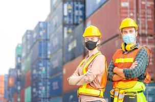 succes teamwork concept, zakenmensen ingenieur en arbeidersteam die beschermingsgezichtsmasker dragen tegen coronavirus met gekruiste armen als teken van succes wazig containerdoos achtergrond foto