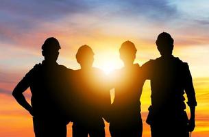 succes en teamwork concept, silhouet van ingenieur en arbeidersteam met uitknippad staande met de handen op de schouders zonsondergang achtergrond foto