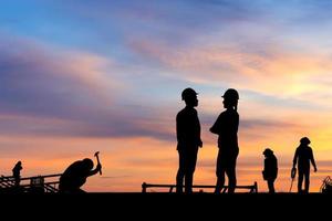 silhouet van ingenieur en werknemer op bouwplaats, bouwplaats bij zonsondergang in de avondtijd foto