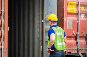 ingenieur arbeider man in veiligheidshelm en veiligheidsvest die containersdoos van lading controleert foto