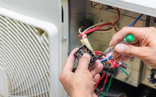 close-up van airconditioningreparatie, reparateur die magnetische schakelaar controleert en airconditioningsysteem bevestigt; foto