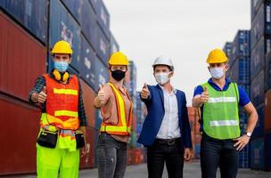 succes teamwork concept, zakenmensen ingenieur en arbeidersteam die een beschermend gezichtsmasker dragen tegen coronavirus met duimen omhoog als teken van succes foto