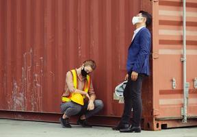 jonge werknemer en ingenieur zitten mislukt en gestrest bij vrachtcontainer foto