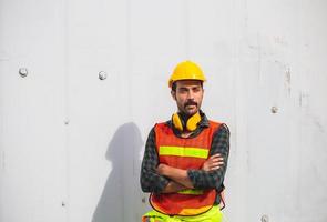 portret van een arbeider die met gekruiste armen bij containerslading staat foto