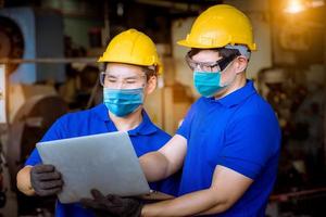 ingenieur onder inspectie en controle van het productieproces op fabrieksstation met schroevendraaier door een veiligheidsmasker te dragen ter bescherming tegen vervuiling en virussen in de fabriek. foto