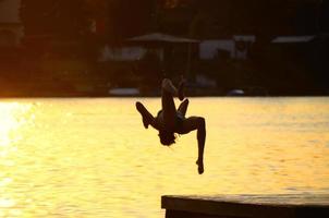 vrouw in bikini die achterwaartse salto doet op het meer foto