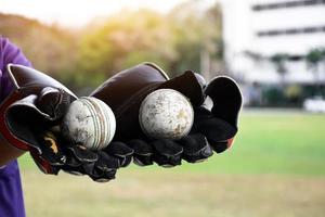 cricketbal voor het oefenen of trainen in de hand, wazig groen grasveld achtergrond, concept voor cricketsportliefhebbers over de hele wereld. foto