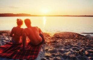 romantisch paar op het strand bij kleurrijke zonsondergangachtergrond foto