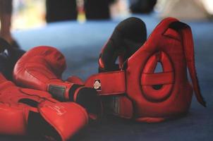 rode bokshandschoenen en hoofddeksel op boksring. foto