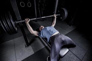 atletische man in sportschool oefenen op de barbell bankdrukken. foto