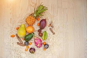 exotische vruchten op houten achtergrond. pitahaya's, carambola's, papaya, baby-ananas, mango, passievrucht, tamarinde, mangosteen, ramboetan, kumquat, avocado en andere. foto