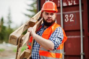 baard werknemer man pak bouwvakker in oranje veiligheidshelm met pallet. foto