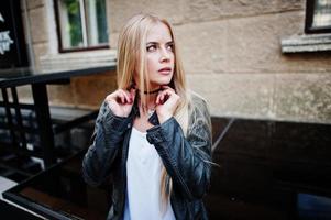 stijlvolle blonde vrouw draagt jeans, choker en leren jas op straat. mode stedelijk model portret. foto