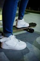 benen van stedelijke tienermeisje op skateboard in skatepark op de avond. foto