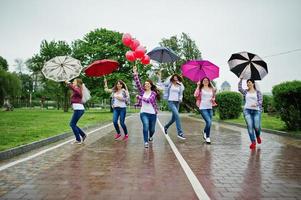 groep van zes meisjes rennen, springen en plezier op vrijgezellenfeest, met paraplu onder regen en ballonnen. foto
