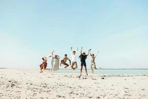 groep opgewonden aziatische mensen die van vakantie genieten met samen springen op het strand foto