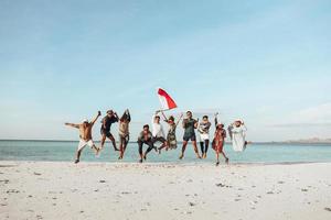 groep mensen die samen op het strand springen om de onafhankelijkheidsdag van Indonesië te vieren foto