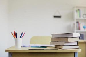 lege schoolbank met briefpapier en stapel boeken foto