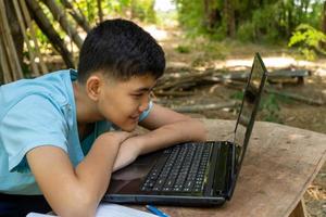 de jongen concentreerde zich gelukkig op het online studeren met zijn laptop thuis in het land foto