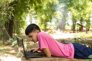 een jongen studeert online met een laptop midden in de natuur thuis op het platteland foto