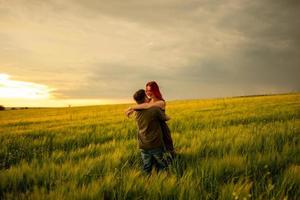 een man en een vrouw liggen op hun rug in een tarweveld. een man kust een vrouw op de wang. het meisje opende haar mond van verrukking. foto