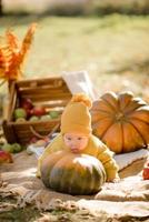 schattig klein meisje zittend op pompoen en spelen in herfstbos foto