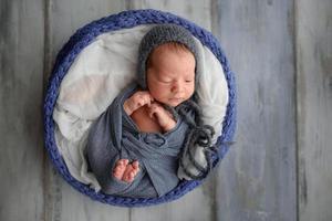 pasgeboren babyjongen gewikkeld in grijze stof foto