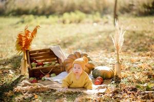 schattig klein meisje zittend op pompoen en spelen in herfstbos foto