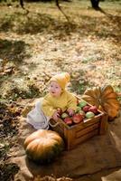 schattig klein meisje zittend op pompoen en spelen in herfstbos foto