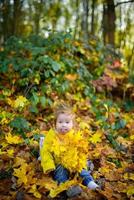 gelukkig meisje lacht en speelt buiten. om de hals hangt een halsketting van herfstbladeren. foto